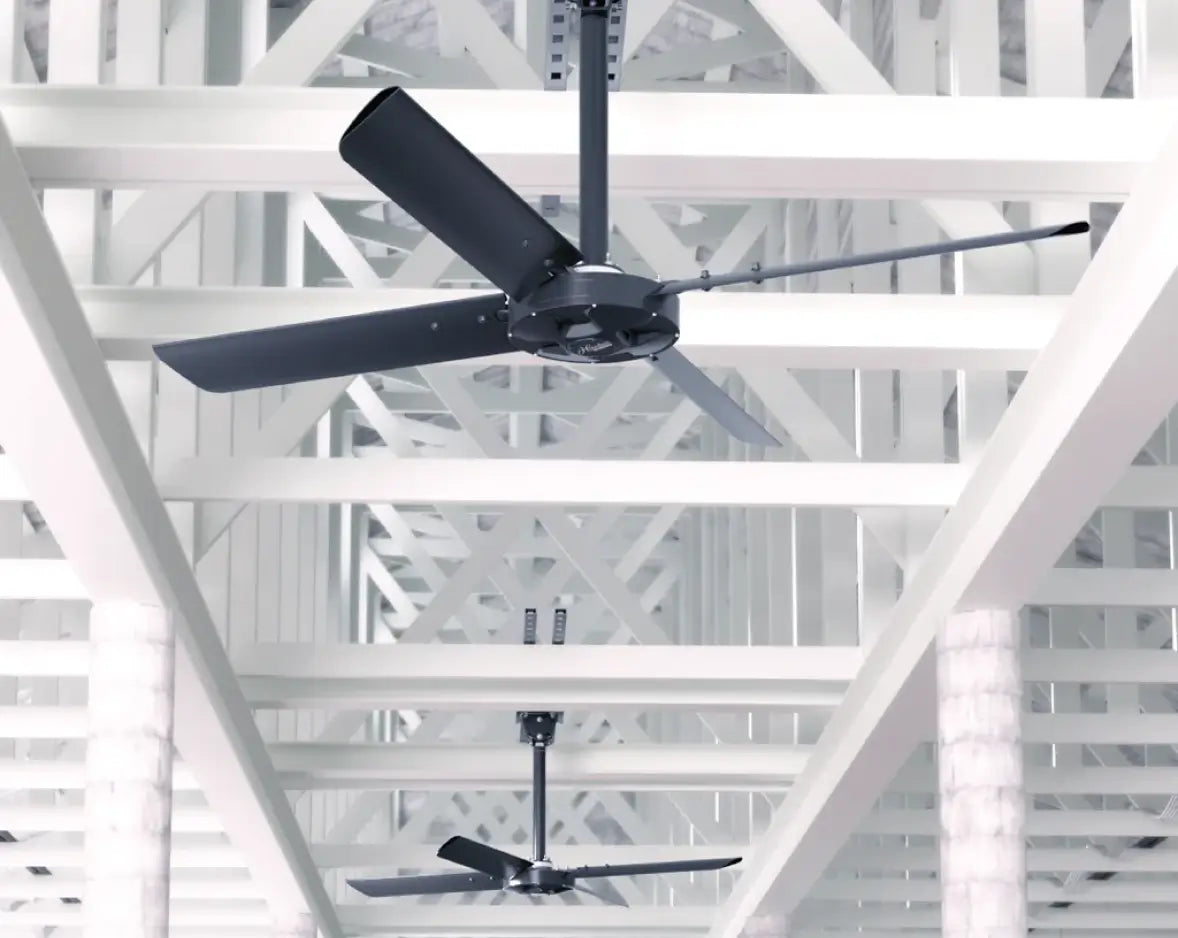 Two Hunter Industrial XP HVLS fans installed in large facility with white steel truss structure